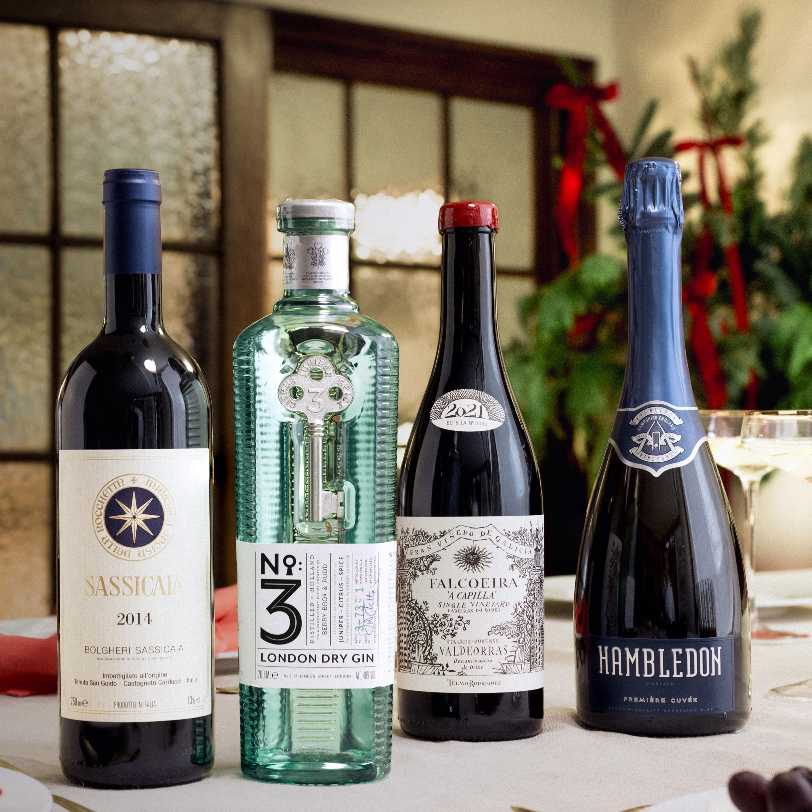 4 bottles of luxury wine, gin, and sparkling wine against a festive backdrop. 